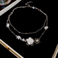 Macro detail of silver double-layered necklace with white flowers and pearls on velvet - Double Layer Necklace