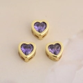Vue détaillée de breloques cœur en cuivre plaqué or avec des cristaux de zircone violets - Violet