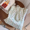 Gros plan du sac fourre-tout en coton fleuri posé sur une table en bois avec des livres - Floral à Rayures Vert Clair