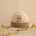 Close-up of knit baby hat showing brown bear embroidery and ribbed texture detail - One Size (6 Months-2 Years) / Beige