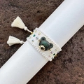 Detail van een handgeweven berenarmband met groene kristallen en witte kwastjes - Wit 1
