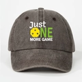Close-up of Just One More Game print with yellow pickleball on washed grey baseball cap - Coffee