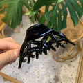 Dettaglio di una grande pinza per capelli nera lucida in un ambiente domestico naturale - Coda di Fenice a Farfalla / Nero Lucido