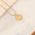 Goldene Schlangenkette mit Sternzeichen-Reliefanhänger auf Marmor- und Holzuntergrund - Zwillinge