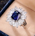 Macro shot of an elegant emerald-cut blue gemstone ring with floral halo zirconia setting - Ur0699