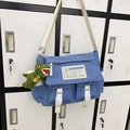 Blue nylon messenger bag in workwear style with white strap and green plush dinosaur charm - Blue + Dinosaur Pendant