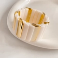 Close-up of geometric cream and gold stretch bracelet on a white ceramic tray - Creamy White & Gold Splicing