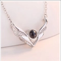 Macro detail of silver V-shaped wing necklace pendant with tiny crystals and round black stone - Antler Silver