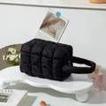 Schicke gesteppte Handtasche in Schwarz auf einem minimalistischen Display-Ständer - Schwarz