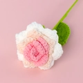 Nahaufnahme einer handgehäkelten Rose mit rosa Farbverlauf und grünem Stiel auf rosa Grund - Verlauf Koreanisch Rosa