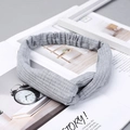 Close-up of a grey ribbed knit cross-knot headband set against a minimalist backdrop - Knitted Light Grey