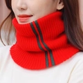 Detail van rode gebreide nekwarmer met groen-donkere strepen op zachte geribbelde stof - Rood