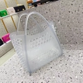Translucent grey hollowed-out jelly tote bag with honeycomb patterns on a minimalist floor - Clear