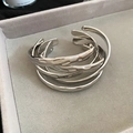 Macro shot of silver hammer-textured open bangles on grey velvet jewelry box padding - Five-Piece Set / Silver