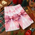 Asciugamano di Natale rosa con motivi di renne e Babbo Natale su un tavolo di legno - Motivo Fiocco a Quadretti Rosa