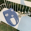 Detail einer hellblauen Stricktasche mit weißen Gänseblümchen auf einer Gartenbank - Himmelblau