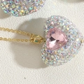 Dettaglio del ciondolo a cuore rosa con strass cangianti su una collana a catena dorata - Zirconia Rosa (XL2601-4)