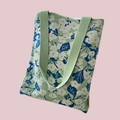 Detail view of the green knit tote bag featuring white floral patterns on a pink background - Light Green White Floral