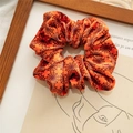 Detailed close-up of an orange velvet scrunchie with black spider web patterns for Halloween - Orange Spider Web
