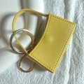 Dettaglio del portachiavi porta rossetto in pelle giallo brillante con anelli dorati - Giallo