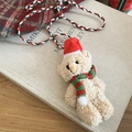 Détail d'un pendentif ours en peluche beige avec bonnet de Noël et écharpe rayée - Style Ours en Peluche