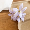 Gros plan sur une épingle à cheveux fleur en tissu lilas avec gouttes d'eau et fil doré - Bleu