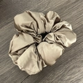 Chouchou élégant en satin de soie beige sur fond en bois sombre pour chignons chic - Champagne