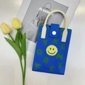 Detailed view of blue knitted phone bag with yellow smiley face and leather strap - Smiley Face Blue