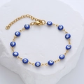 Macro detail of golden stainless steel evil eye bracelet with blue enamel charms - Blue