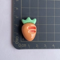 Detailed view of glossy resin carrot charm showing dimensions on a scale mat - Orange Carrot