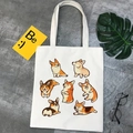 White canvas tote bag featuring cute cartoon corgi prints with modern aesthetic props - 7 Corgis Illustration