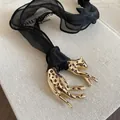Luxuriöse Leoparden-Halskette in Gold-Optik mit schwarzem Stoffband auf Buch - Goldbraun