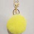 Close-up of bright yellow faux rabbit fur keychain with gold lobster clasp and ring - Yellow