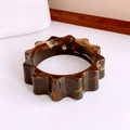 Macro detail of tortoiseshell acrylic bangle with unique wavy gear-shaped decorative edges - Dark Coffee