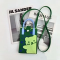 Detail of green knitted cartoon bear phone bag featuring metal button closure and blue handles - Green Bear