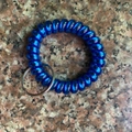Macro view of a dark blue spiral telephone cord wrist keychain with silver metal ring - Metallic Royal Blue