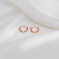 Minimalist gold hoop earrings with red polka dots displayed on white silk texture - Fuschia