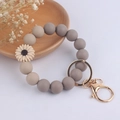 Détail du bracelet porte-clés en perles de silicone gris avec marguerite et fermoir doré - Marguerite Beige