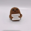 Handmade crochet positive potato doll in brown yarn holding a German support card - German Card Large Potato