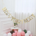 Striscione dorato Happy Birthday con font metallico e palloncini decorativi rosa - Stile Vuoto / Oro