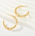 Close-up of 18K gold C-shaped earrings with vintage bamboo texture on white wave base - Gold-Toned Bamboo Textured Hoops (Style 5)