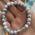 Bracciale di turchese bianco con ciondolo a manubrio d'argento sul palmo aperto - Pino a Linee Bianche Argento Elastico