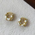 Vintage gold hoop earrings with white enamel waves and zircon accents on stone surface - White