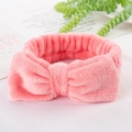 Detailed view of a soft pink coral fleece headband with a large decorative bow - Watermelon red