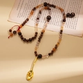 Dettaglio della collana etnica con perline, ciondolo a cucchiaio d'oro e nappe rosse - Collana - Oro