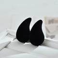 Macro shot of black velvet teardrop earrings in a white gift box with soft texture - Black