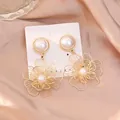 Elegant gold hollow flower drop earrings with white pearls on champagne silk fabric - Style 25092909-2