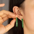 Long green gemstone earrings with gold base hanging on the model's ear - Long Square Green Gemstone Style (E592-GO-G)