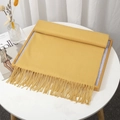 Ginger yellow faux cashmere scarf with fringe tassels neatly folded on wooden frame - Goose Yellow