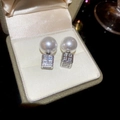 Détail macro de boucles d'oreilles perles et zircons carrés sur présentoir en velours beige - Argenté